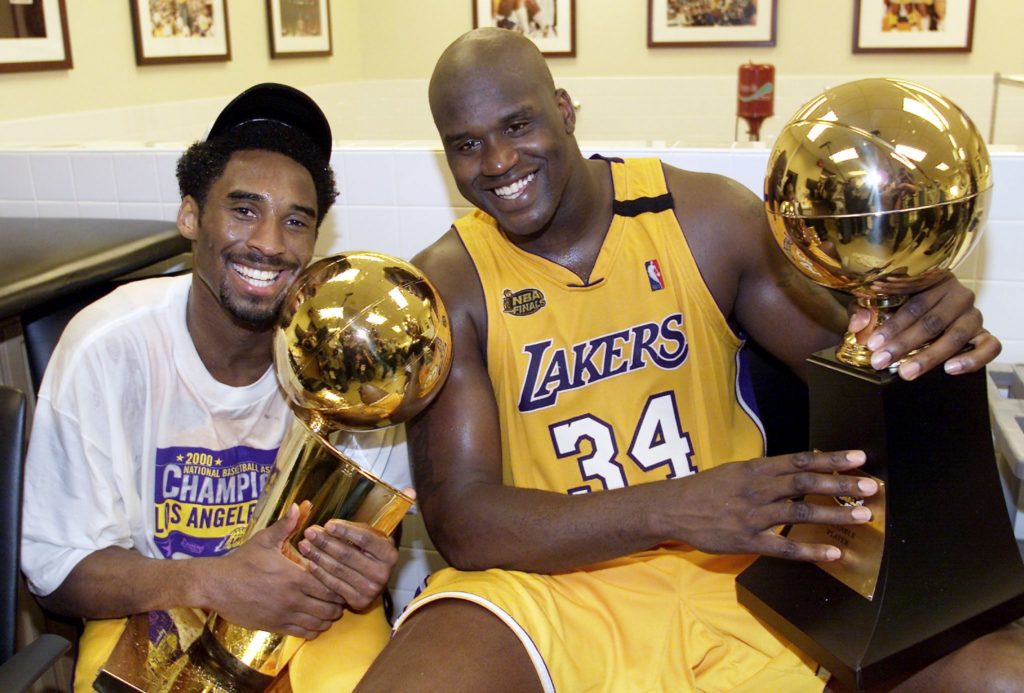 Kobe Bryant (L) of the Los Angeles Lakers holds the Larry O'Brian trophy as teammate Shaquille O'Neal (L) hold the MVP trophy after winning the NBA Championship against Indiana Pacers 19 June, 2000, after game six of the NBA Finals at Staples Center in Los Angeles, CA. The Lakers won the game 116-111 to take the NBA title 4-2 in the best-of-seven series. (ELECTRONIC IMAGE) AFP PHOTO (Photo by - / AFP) (Photo by -/AFP via Getty Images)