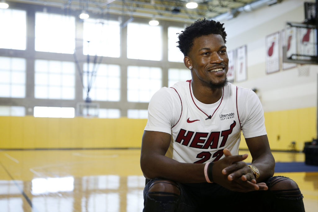 Jimmy Butler sits smiling with Miami Heat jersey on