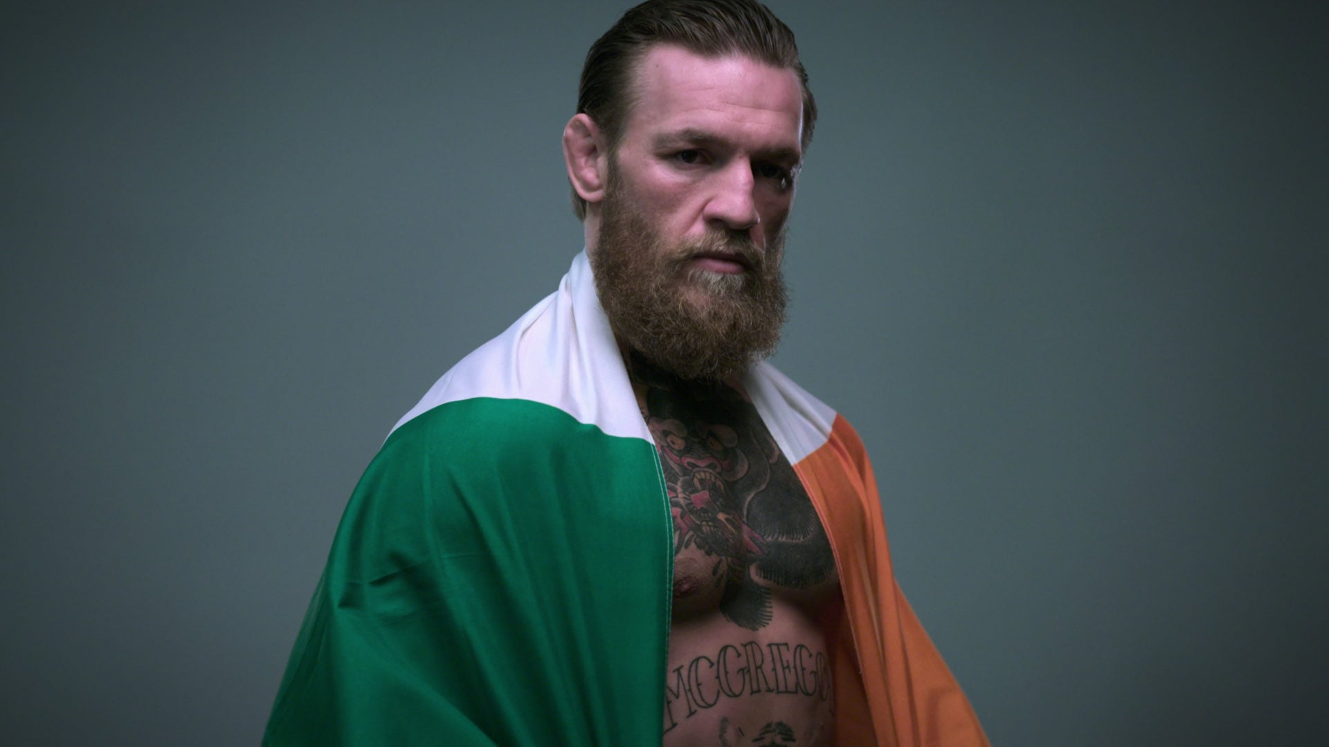 Conor McGregor stands with an ROI flag around his shoulder