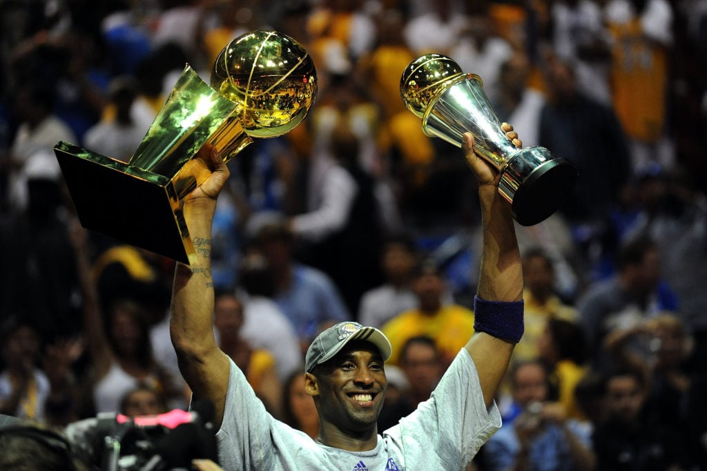 Kobe Bryant #24 of the Los Angeles Lakers holds up the Larry O'Brien trophy and the Bill Russell MVP trophy after the Lakers defeated the Orlando Magic 99-86 in Game Five of the 2009 NBA Finals on June 14, 2009 at Amway Arena in Orlando, Florida.