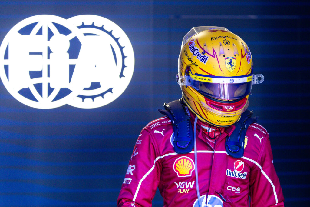Lewis Hamilton standing in front of a lit-up FIA sign at the 2025 Emilia Romagna Grand Prix.