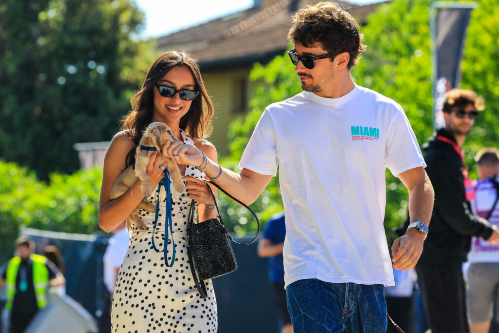Charles Leclerc and Alexandra Saint Mleux walk through the paddock with their dog Leo Leclerc