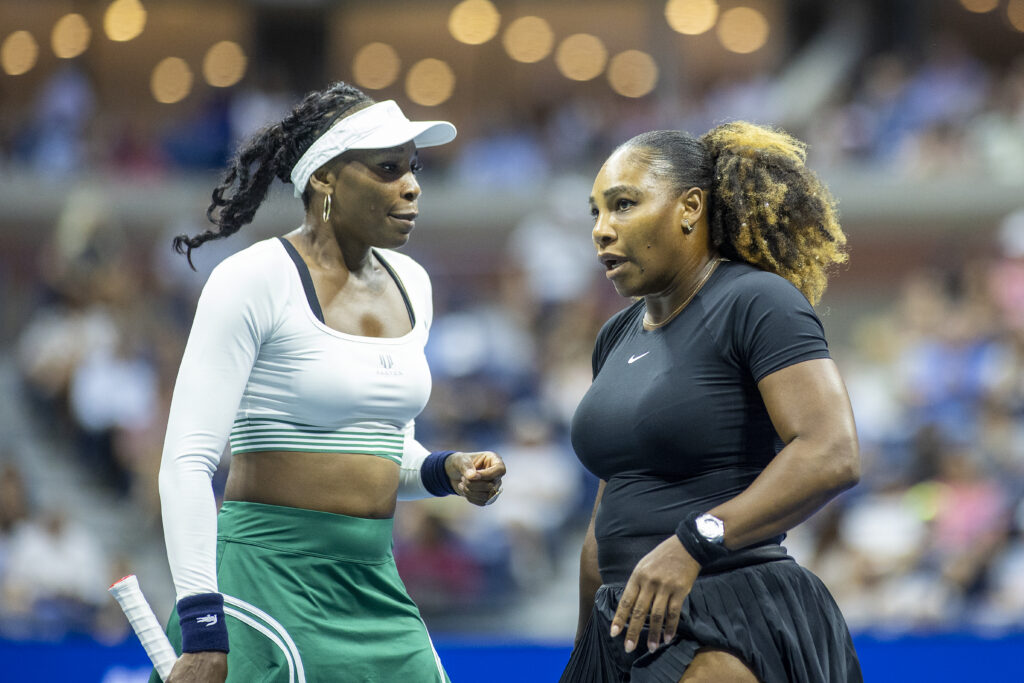 Venus and Serena Williams playing doubles together at the 2022 US Open.