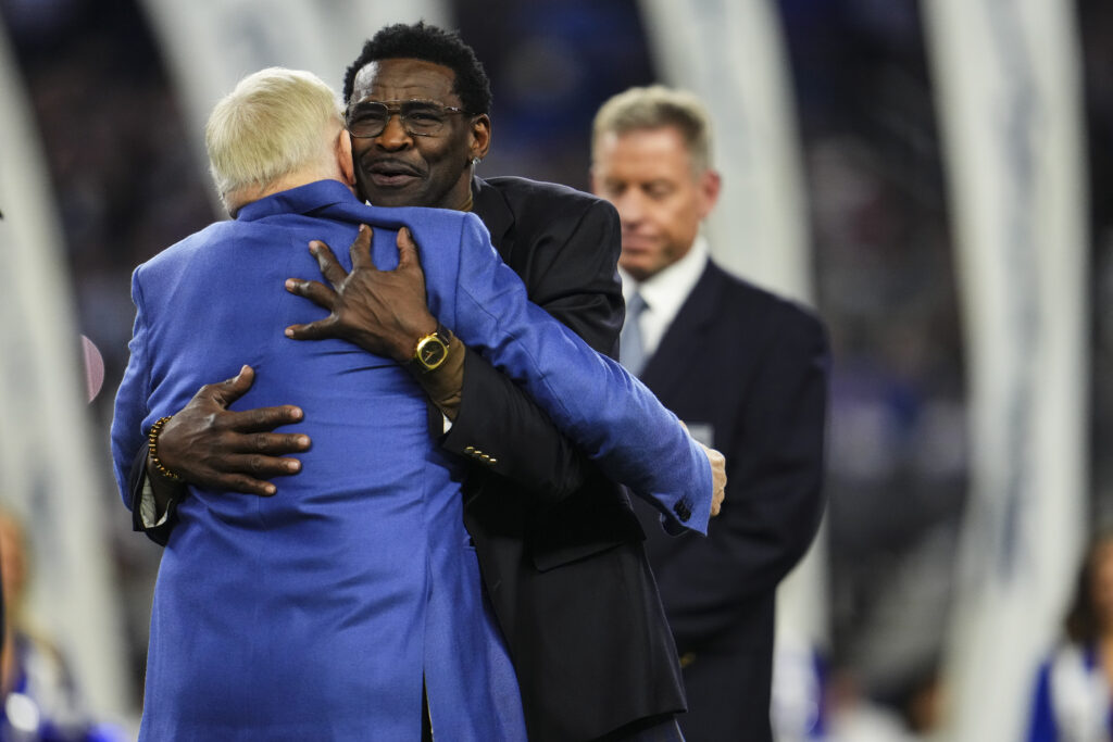Former NFL player Michael Irvin embraces Dallas Cowboys owner Jerry Jones at halftime during an NFL football game between the Detroit Lions and the Dallas Cowboys at AT&T Stadium on December 30, 2023 in Arlington, Texas.