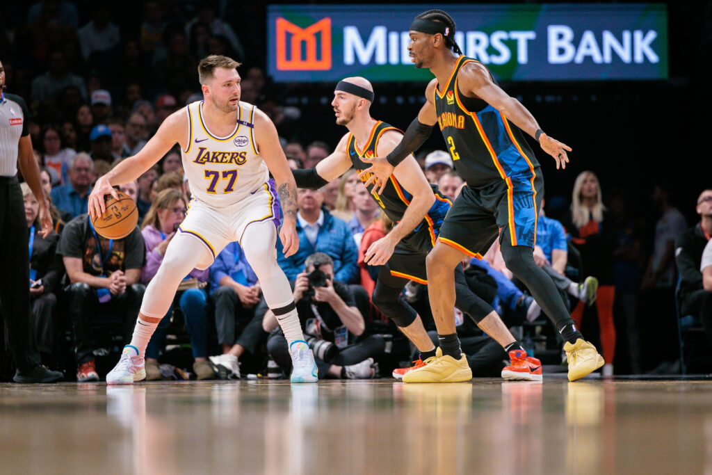 Luka Doncic #77 of the Los Angeles Lakers drives to the basket around Shai Gilgeous-Alexander #2 of the Oklahoma City Thunder and Alex Caruso #9 of the Oklahoma City Thunder during the first quarter at Paycom Center on April 6, 2025 in Oklahoma City, Oklahoma.