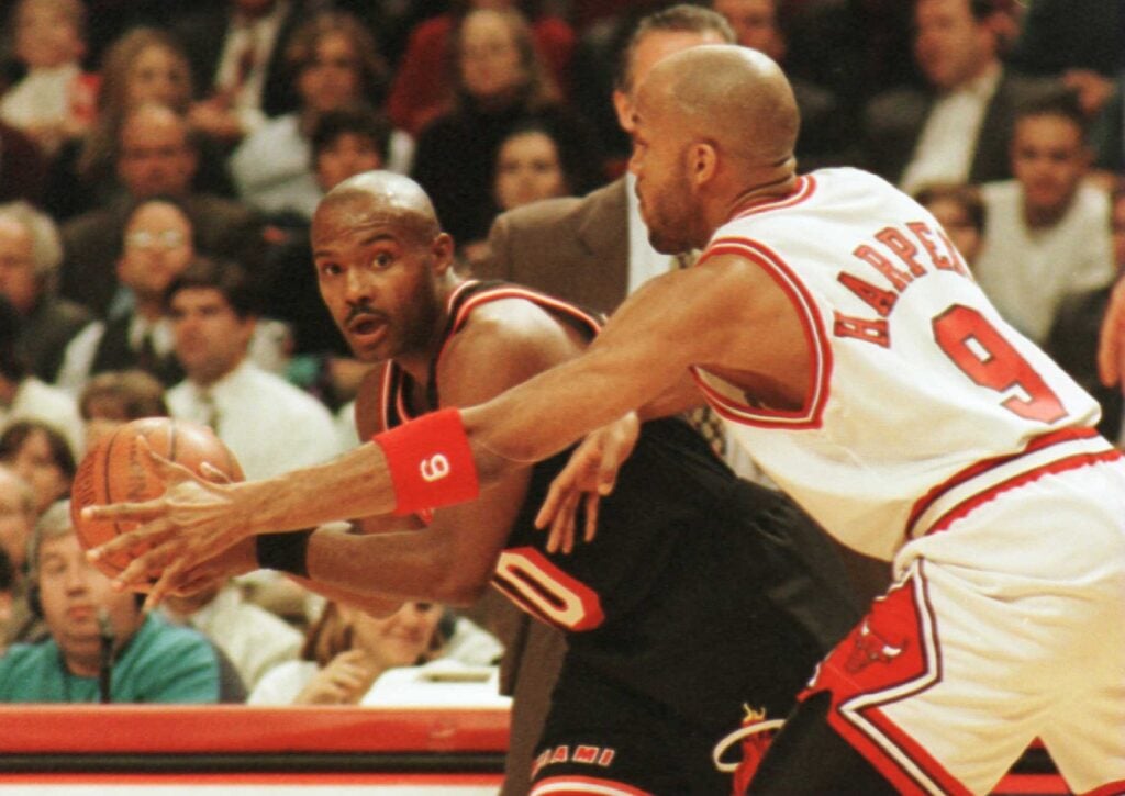 Guard Tim Hardaway of the Miami Heat looks for an open teammate around the reaching arm of guard Ron Harper of the Chicago Bulls during first quarter action of their game at the United Center.