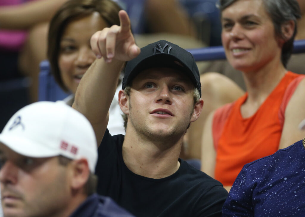 Niall Horan watches the tennis, pointing