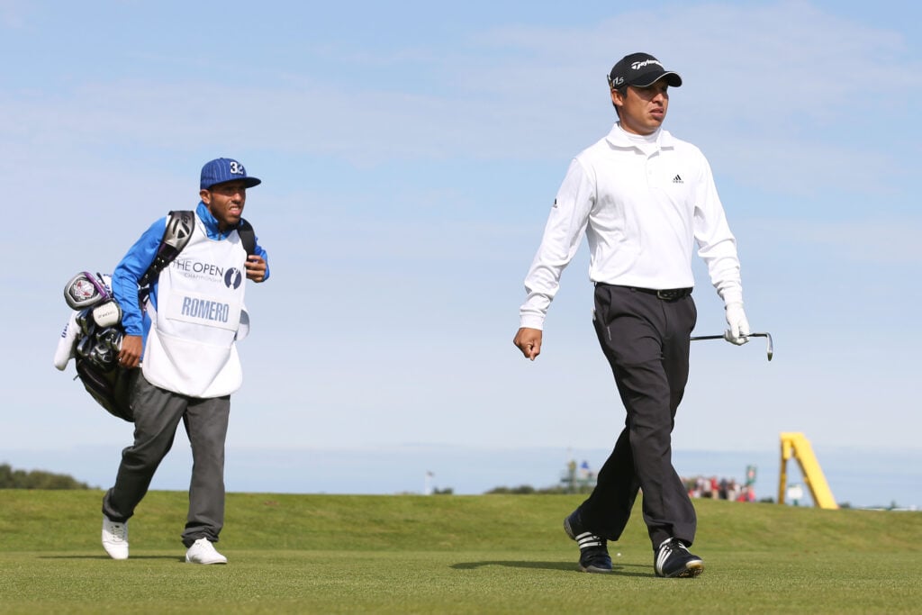 Andres Romero of Argentina and his guest caddie, footballer Carlos Tevez of Manchester City and Argentina walk off the ninth tee during the final round of the 141st Open Championship 2012