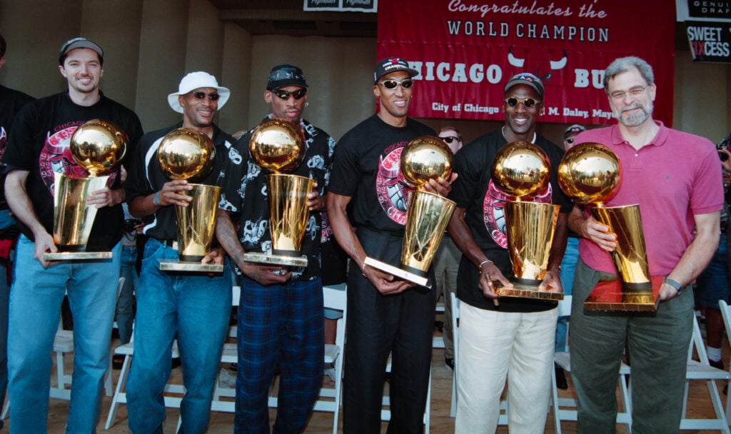 Members of the Chicago Bulls basketball team pose with trophies at a rally to celebrate the team's sixth NBA Championship victory.