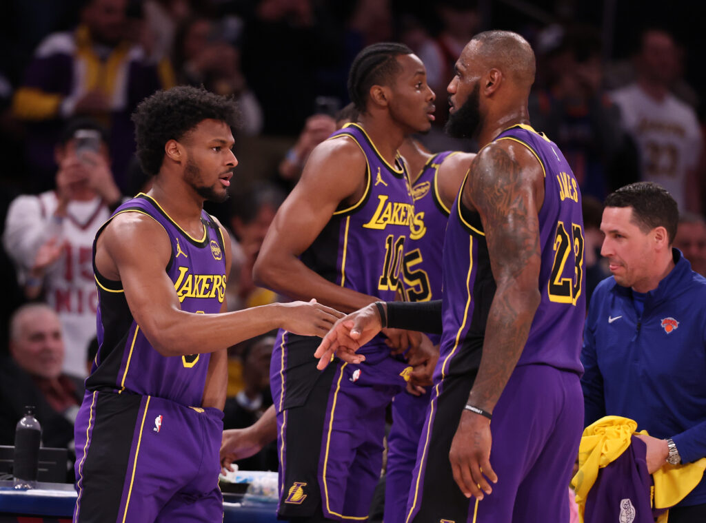 Bronny James #9 of the Los Angeles Lakers shakes hands with LeBron James #23 of the Los Angeles Lakers before entering the game in the fourth quarter against the New York Knicks.