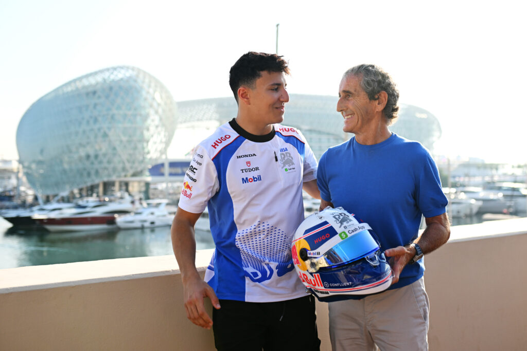 Isack Hadjar hands former Formula 1 champion Alain Prost his 2025 Racing Bulls helmet ahead of the final race in Abu Dhabi