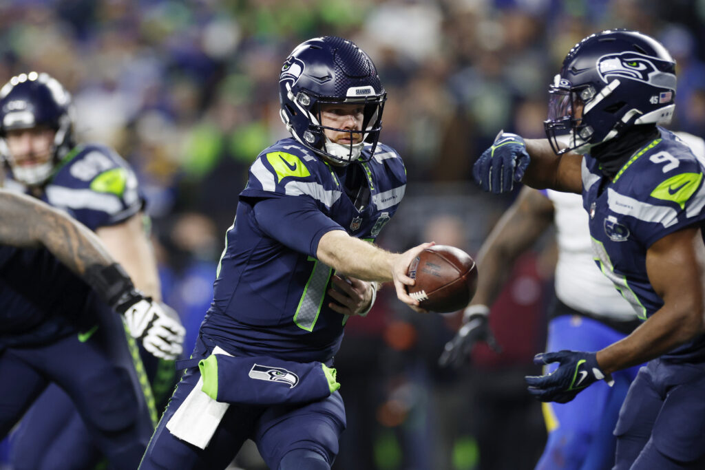 Sam Darnold #14 of the Seattle Seahawks turns to hand off to Kenneth Walker III #9 during the NFC Championship game against the Los Angeles Rams on January 25, 2026 at Lumen Field in Seattle, Washington.