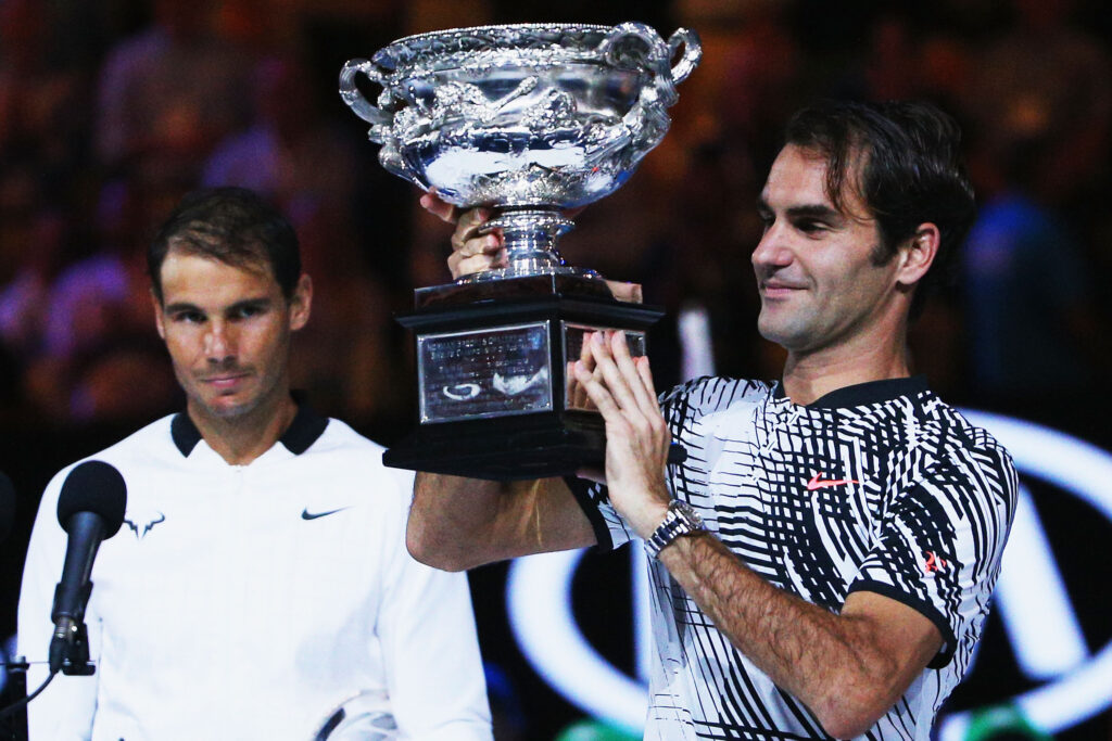 A defeated Rafael Nadal of Spain reacts as Roger Federer of Switzerland celebrates with the Trophy after winning in the Men's Final match against on day 14 of the 2017 Australian Open at Melbourne Park on January 29, 2017 in Melbourne, Australia.