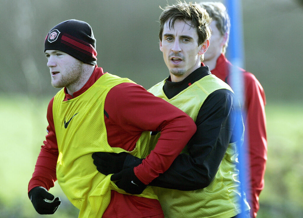 Manchester United footballer Gary Neville (R) holds on to team-mate Wayne Rooney during a training session at the team's Carrington training ground.