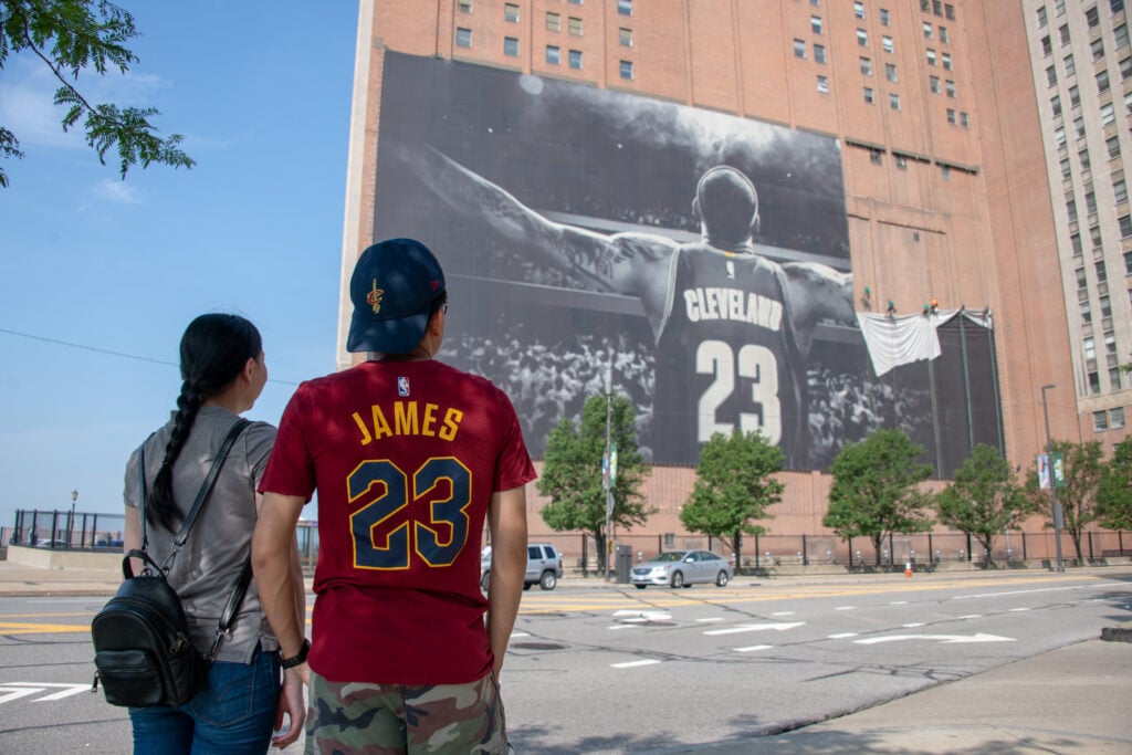 Workers remove the Nike LeBron James banner from the Sherwin-Williams building near Quicken Loans Arena on July 3, 2018.