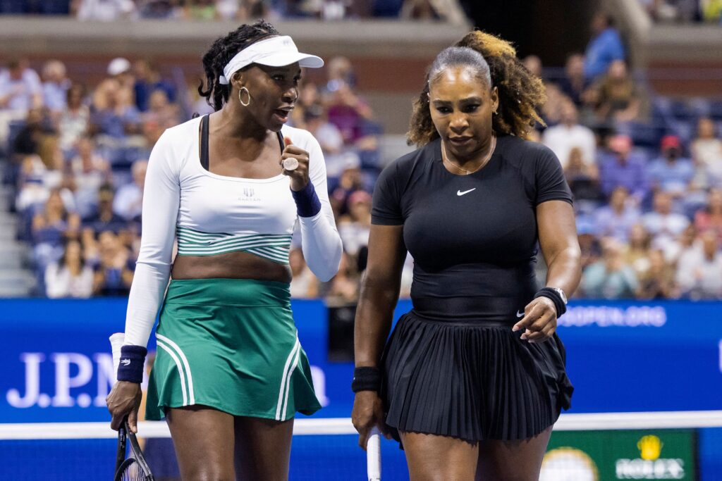 Serena Williams (R) and Venus Williams confer as they play against Czech Republic's Lucie Hradecka and Linda Noskova during their 2022 US Open Tennis tournament women's doubles first round match at the USTA Billie Jean King National Tennis Center.