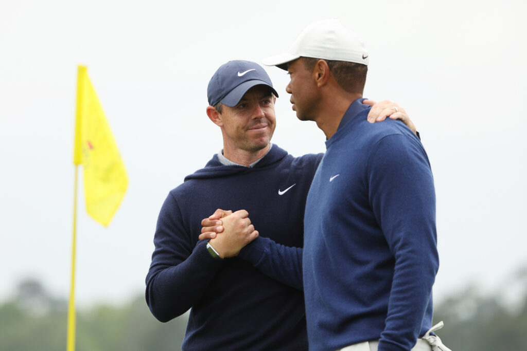 Rory McIlroy of Northern Ireland and Tiger Woods of the United States shake hands on the 18th green during a practice round prior to the 2023 Masters Tournament at Augusta National