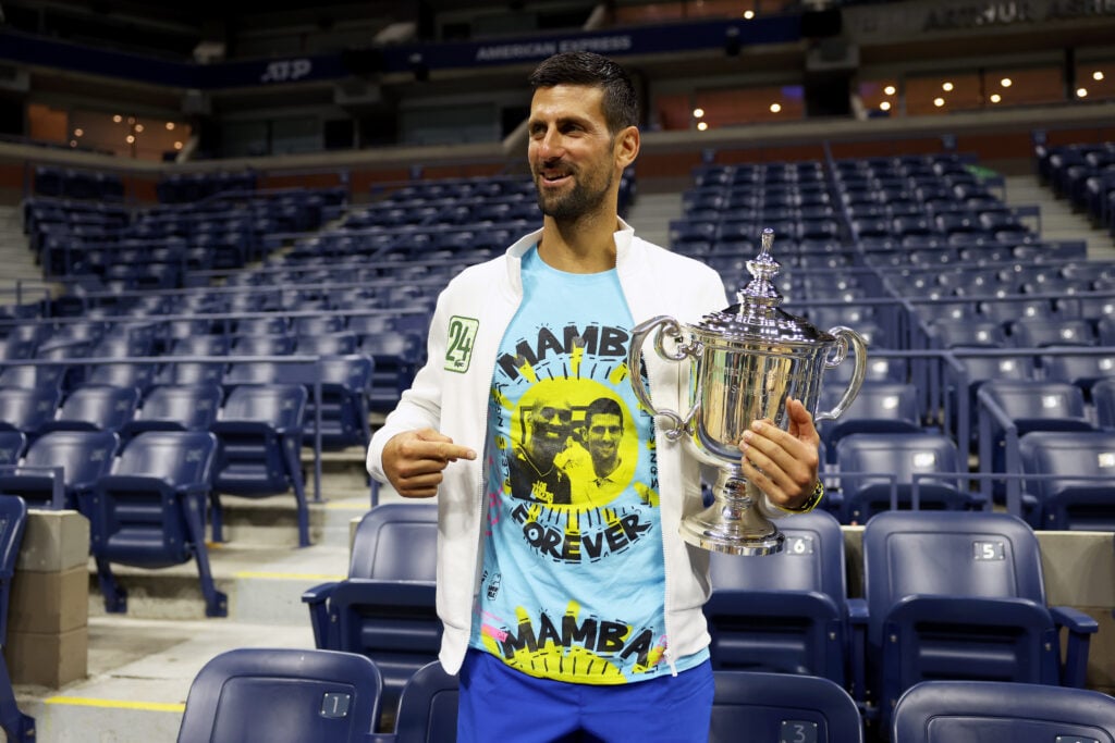 Novak Djokovic of Serbia poses for the media with his winners trophy wearing a shirt as a tribute to the late Kobe Bryant