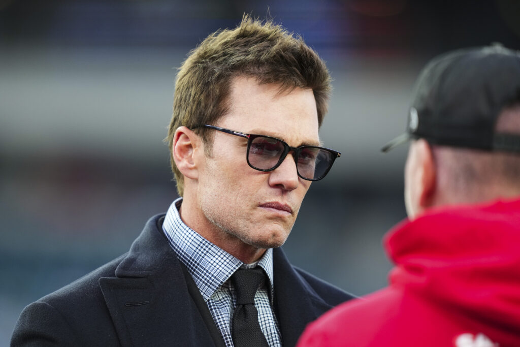 Tom Brady looks on from the field during warmups prior to an NFL wild card playoff football game between the San Francisco 49ers and the Philadelphia Eagles at Lincoln Financial Field on January 11, 2026 in Philadelphia, Pennsylvania.
