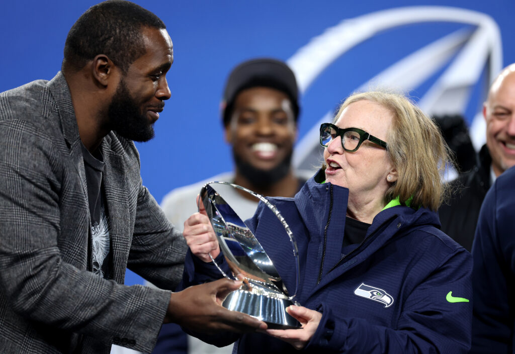 Former Seattle Seahawks player Kam Chancellor hands the George Halas Trophy to Jody Allen of the Seattle Seattle Seahawks after Seattle defeated the Los Angeles Rams 31-27 in the NFC Championship game at Lumen Field.