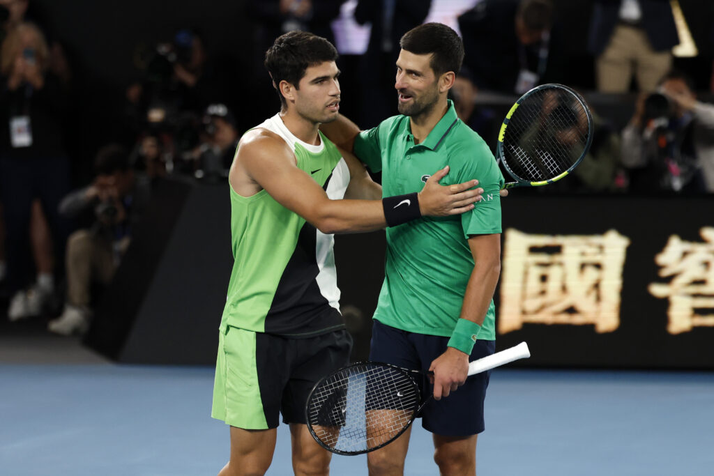 Carlos Alcaraz of Spain embraces Novak Djokovic of Serbia after his victory in the Men's Singles Final during day 15 of the 2026 Australian Open at Melbourne Park on February 01, 2026 in Melbourne, Australia.