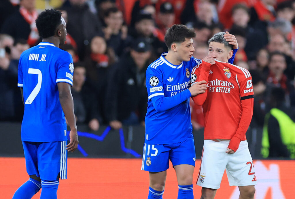SL Benfica's Argentine forward #25 Gianluca Prestianni hides his mouth while arguing with Real Madrid's Brazilian forward #07 Vinicius Junior who complained about alleged racists insults during the UEFA Champions League knockout round play-off first leg football match between SL Benfica and Real Madrid CF at Estadio da Luz in Lisbon.