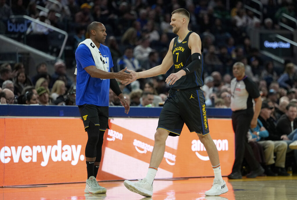Kristaps Porzingis #7 of the Golden State Warriors slaps hands with teammate Al Horford #20 as Porzingis walks off the court against the Boston Celtics in the first half at Chase Center.