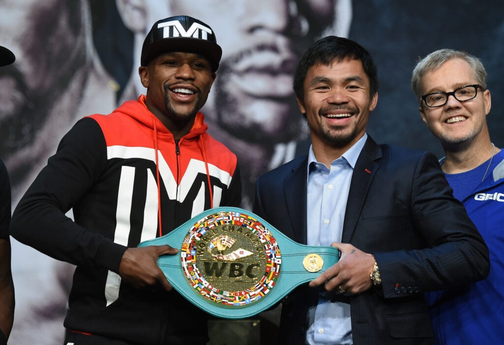 WBC/WBA welterweight champion Floyd Mayweather Jr. and WBO welterweight champion Manny Pacquiao pose with a WBC championship belt as Pacquiao's trainer Freddie Roach looks on during a news conference at the KA Theatre at MGM Grand Hotel & Casino on April 29, 2015 in Las Vegas, Nevada. The two will face each other in a unification bout on May 2, 2015 in Las Vegas.