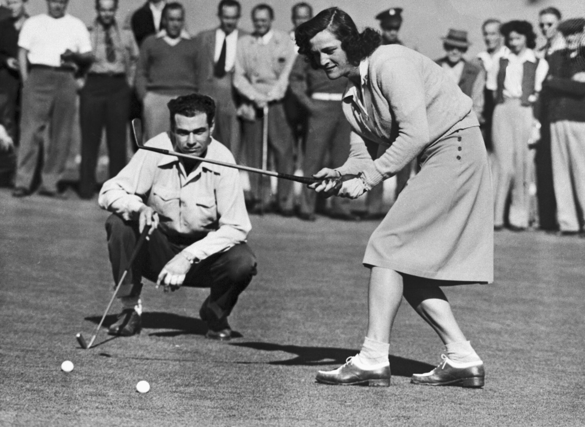 Babe Didrikson Zaharias drops a putt for a par four to halve first hole with Howard Teeter in their golf match at Brookside Park in the Pasadena Ci...