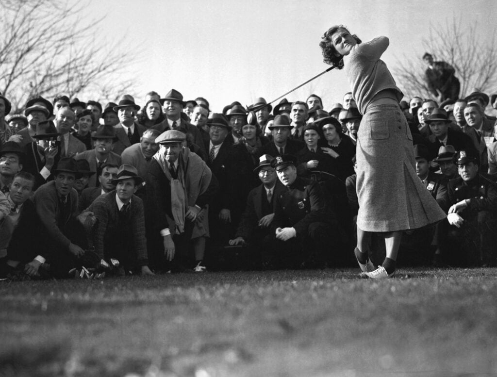 Mildred "Babe" Didrikson, golf star from Texas, driving off, as the gallery hems her in, in the four-ball charity golf match at Fresh Meadow Country Club,