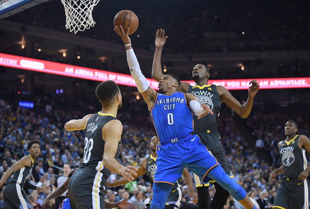 Russell Westbrook #0 of the Oklahoma City Thunder goes up for a layup in front of Kevin Durant #35 of the Golden State Warriors and gets fouled by Stephen Curry #30 during the first half of their NBA basketball game at ORACLE Arena on February 6, 2018.