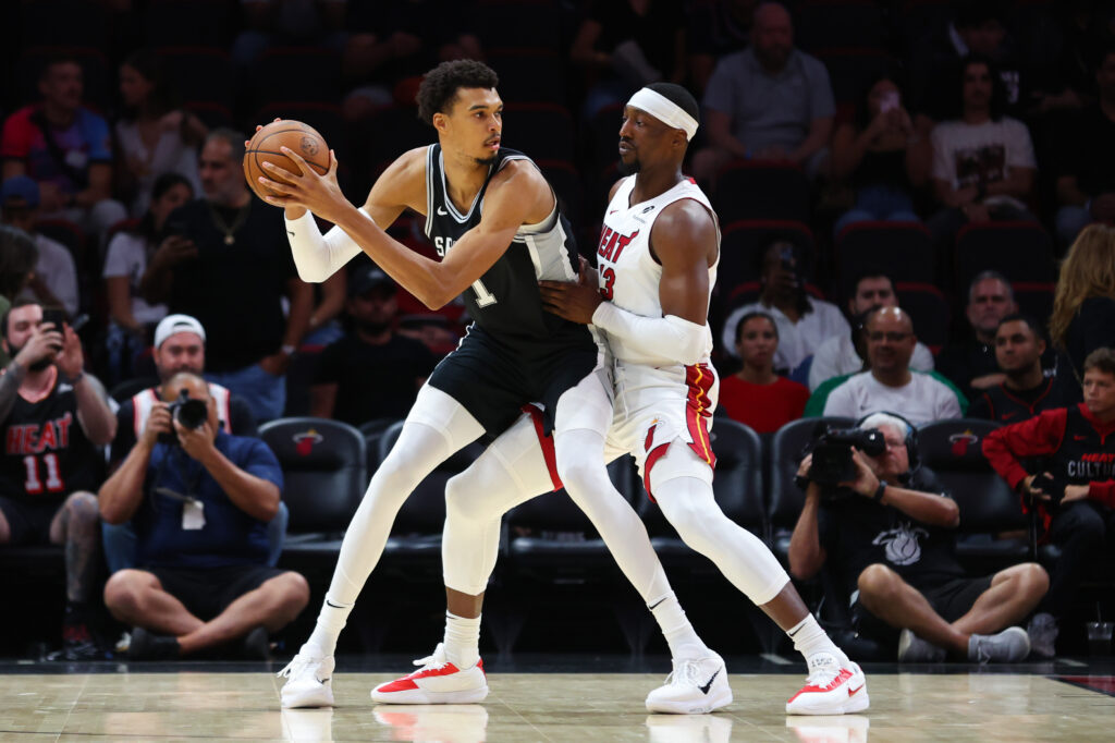 Victor Wembanyama #1 of the San Antonio Spurs drives against Bam Adebayo #13 of the Miami Heat during the first quarter of a preseason game at Kaseya Center.