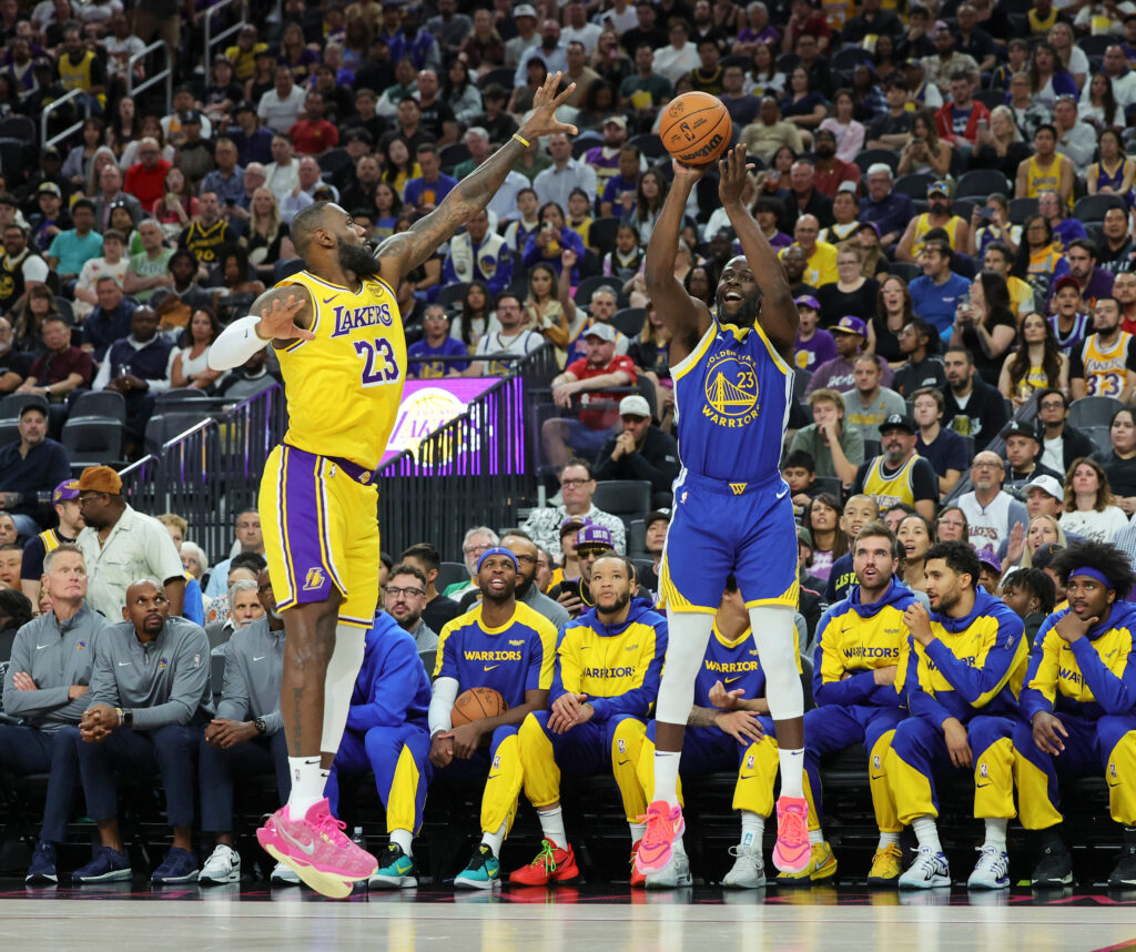 Draymond Green #23 of the Golden State Warriors shoots a 3-pointer against LeBron James #23 of the Los Angeles Lakers in the first quarter of their preseason game at T-Mobile Arena at T-Mobile Arena on October 15, 2024 in Las Vegas, Nevada. The Warriors defeated the Lakers 111-97.