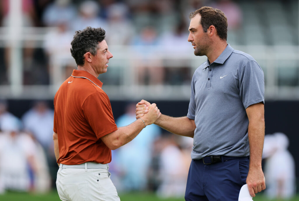 Rory McIlroy of Northern Ireland, left, shakes hands with Scottie Scheffler of the United States on the 18th hole green after finishing the second round of the PGA Championship at Quail Hollow