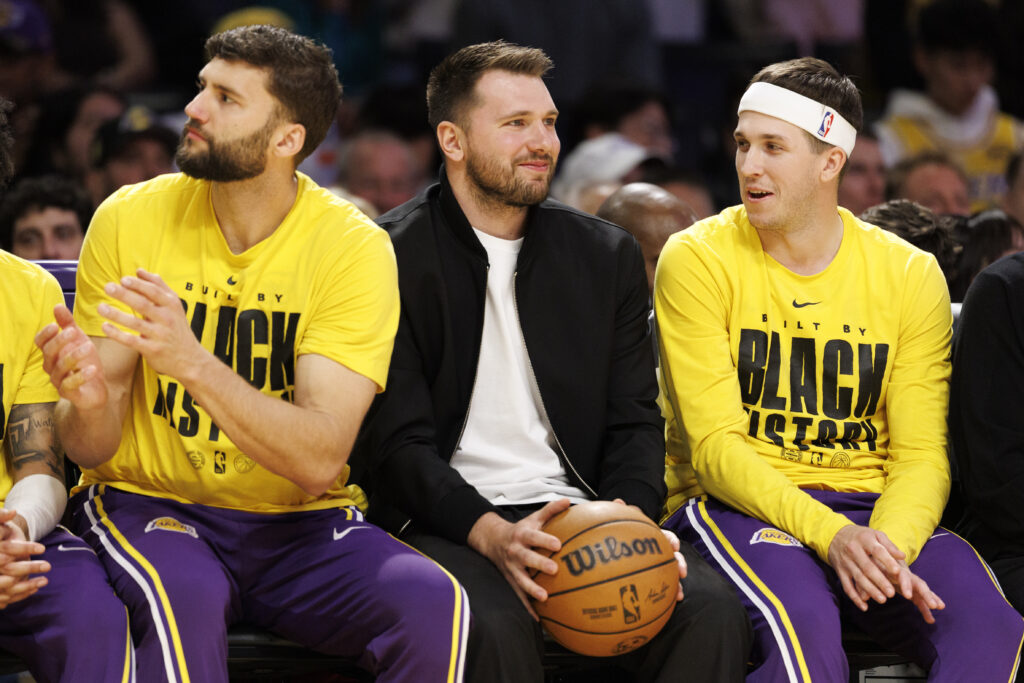 Injured Los Angeles Lakers guard Luka Doncic (77) sits on the bench in street clothes next to Los Angeles Lakers forward Maxi Kleber (14) and Los Angeles Lakers guard Austin Reaves (15), right, during the game against the Golden State Warriors at Crypto.com Arena on February 7, 2026.