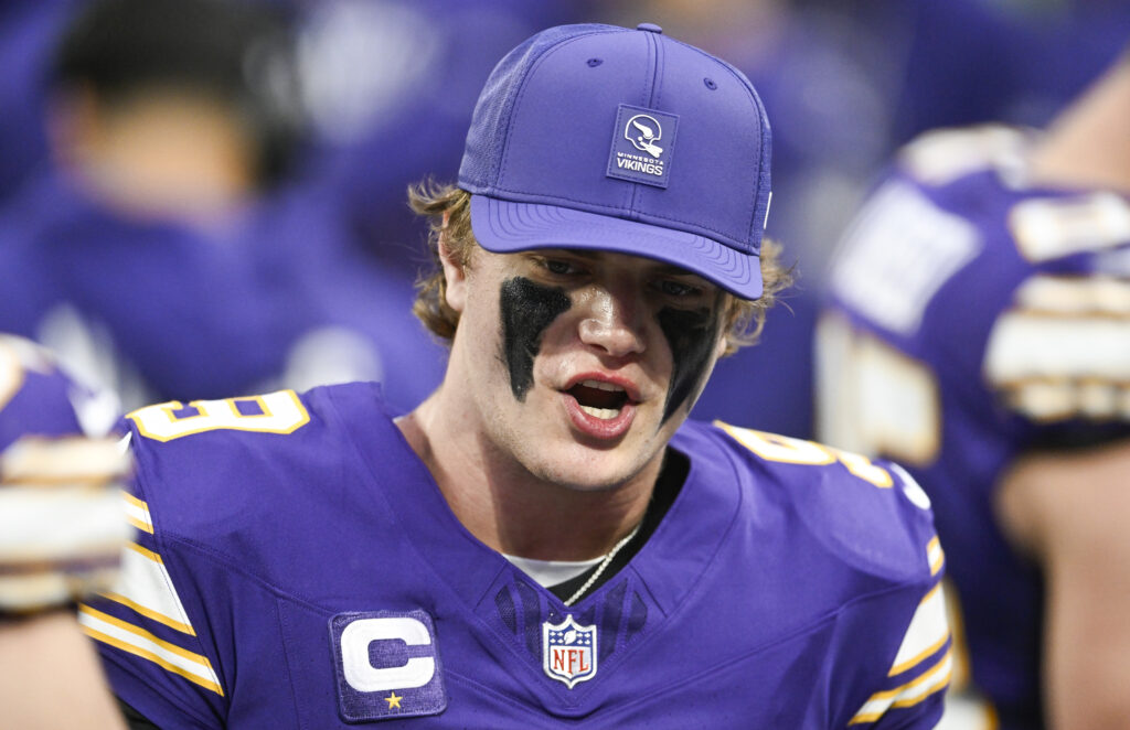 J.J. McCarthy #9 of the Minnesota Vikings speaks with teammates on the bench against the Green Bay Packers in the first quarter of the game at U.S. Bank Stadium on January 4, 2026 in Minneapolis, Minnesota.