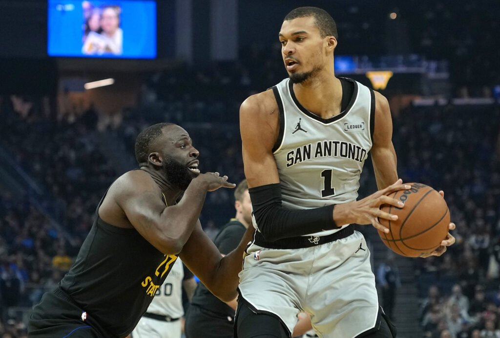 Victor Wembanyama #1 of the San Antonio Spurs posts up against Draymond Green #23 of the Golden State Warriors in the first half at Chase Center.