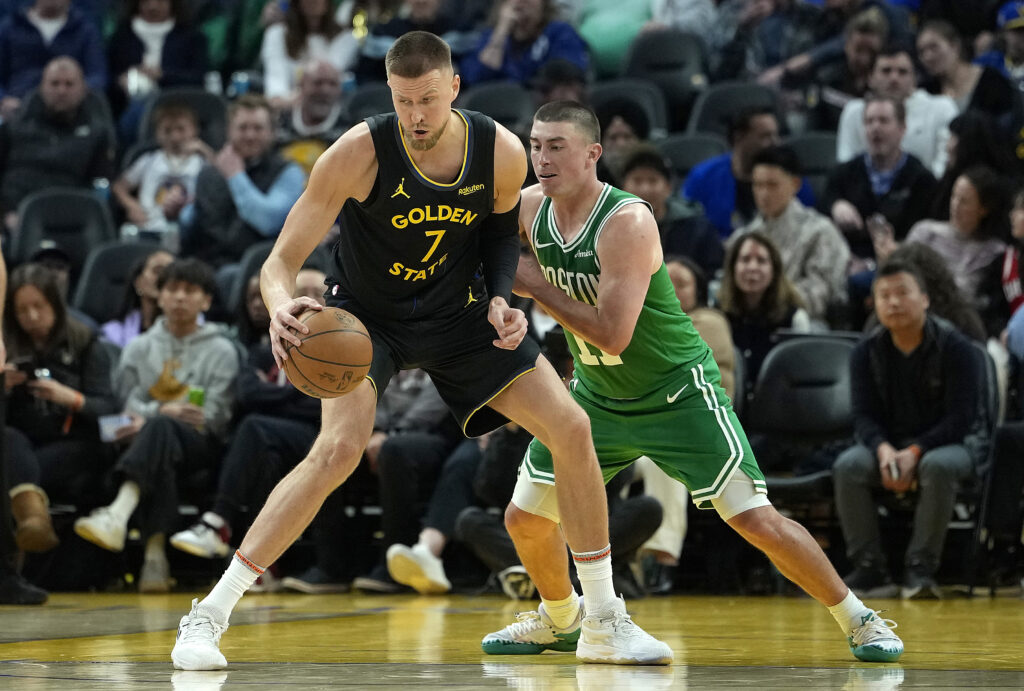 Kristaps Porzingis #7 of the Golden State Warriors dribbling the ball is guarded by Payton Pritchard.