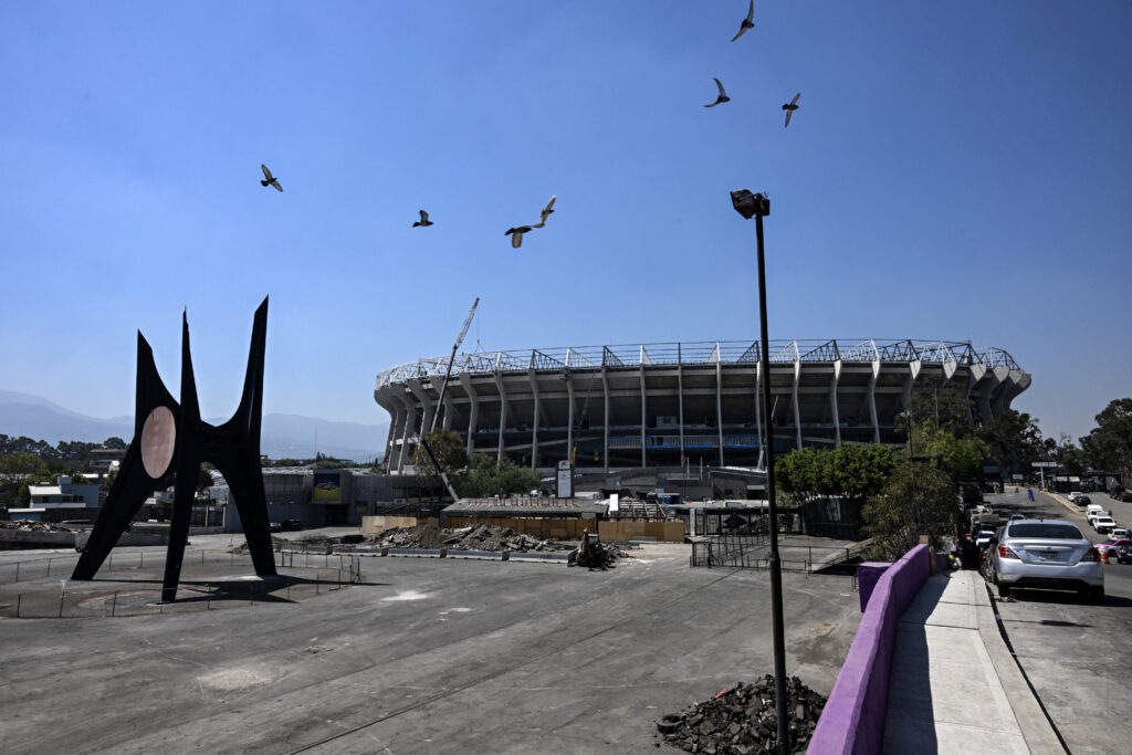 A flock of pigeons flies in front of the iconic Azteca Stadium, which is undergoing renovations to host the opening ceremony of the upcoming FIFA World Cup, in Mexico City on February 23, 2026. Mexico has deployed 10,000 troops to quell clashes sparked by the killing of the country's most wanted drug lord, which have left dozens dead, officials said on February 23. Nemesio "El Mencho" Oseguera, leader of the Jalisco New Generation Cartel.