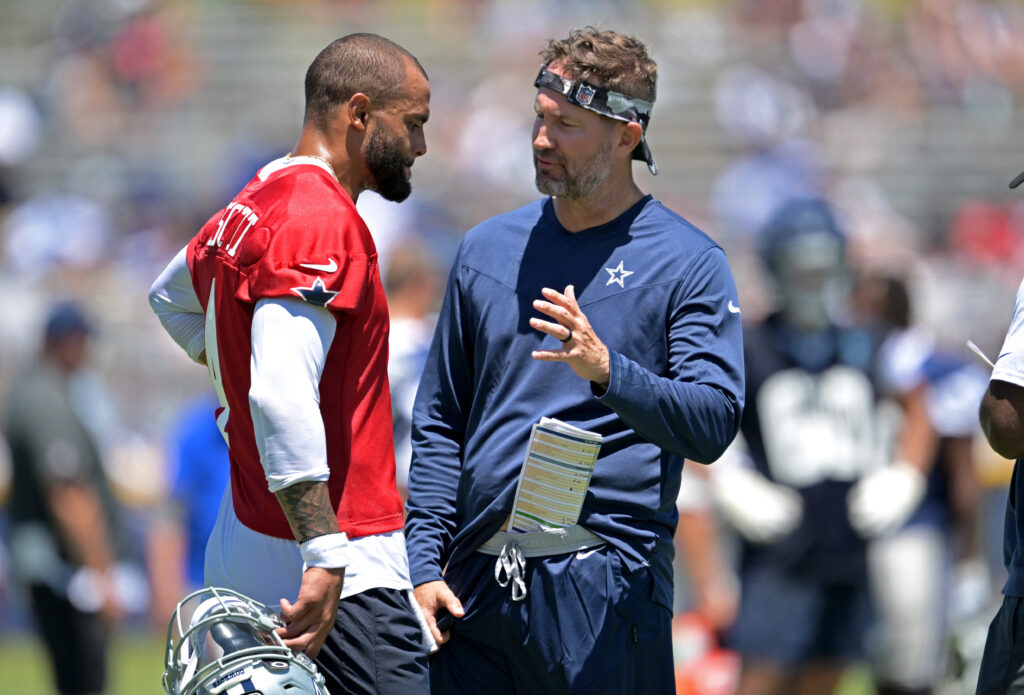 Quarterback Dak Prescott #4 of the Dallas Cowboys talks with offensive coordinator Brian Schottenheimer during training camp at River Ridge Playing Fields.