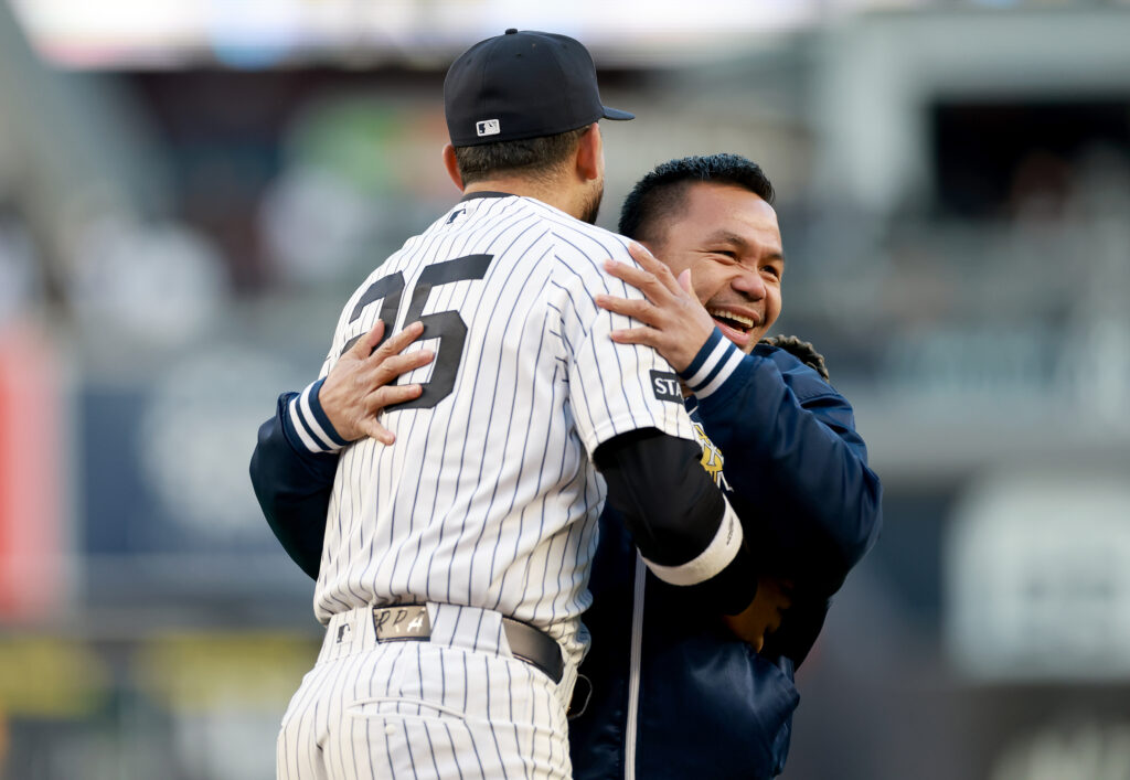 Manny Pacquiao reacts after throwing out the ceremonial first pitch and hugs J.C. Escarra #25 of the New York Yankees before the game between the New York Yankees and the Athletics at Yankee Stadium.