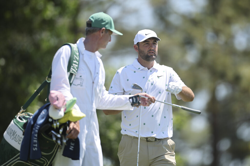 Scottie Scheffler hands a club to his caddie Ted Scott on the fourth hole during the third round of the 2026 Masters Tournament