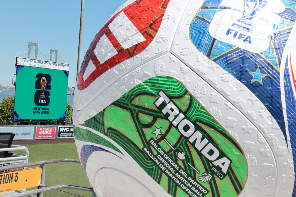 A replica World Cup soccer ball is seen as the FIFA logo is displayed on a screen during a press conference at Staten Island University Hospital Community Park.