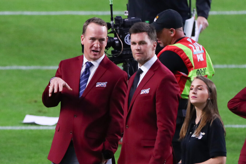 Tom Brady and Peyton Manning talk on the field during the 100 year team celebration prior to Super Bowl LIV on February 2, 2020 at Hard Rock Stadium.