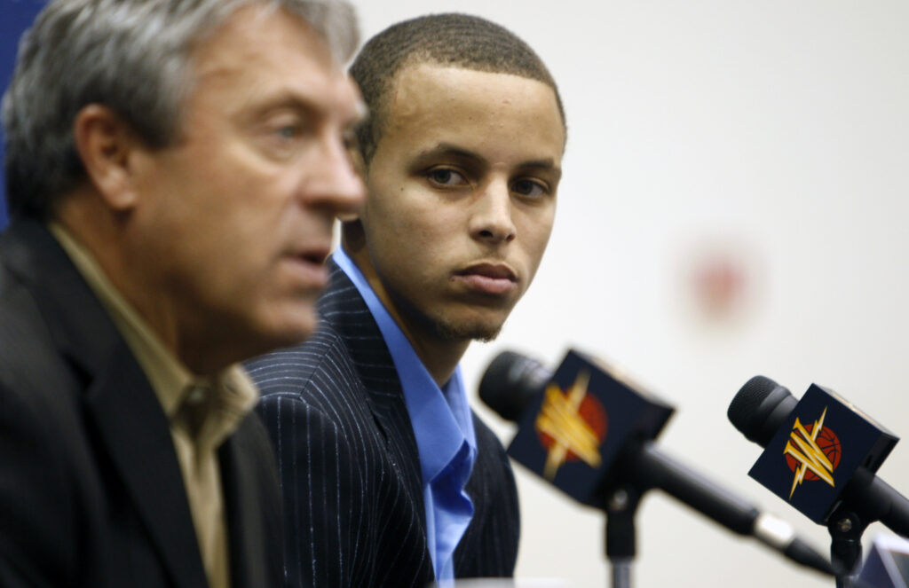 Golden State Warriors top draft pick Stephen Curry right listens to comments by Warriors General Manager Larry Riley about his shooting skills at a press conference at Warriors headquarters.