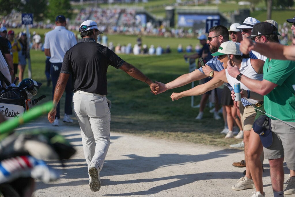 Aaron Rai of England gives knuckles to fans while walking towards the 15th tee box during the final round of PGA Championship at Aronimink Golf Club