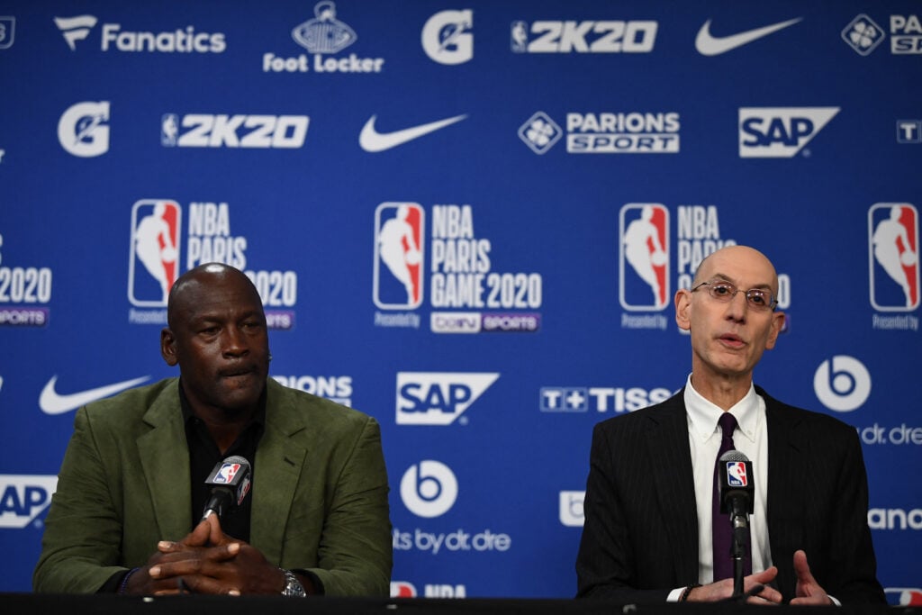 Former NBA star and owner of Charlotte Hornets team Michael Jordan (L) looks on as NBA commissioner Adam Silver addresses a press conference ahead of the NBA basketball match between Milwaukee Bucks and Charlotte Hornets at The AccorHotels Arena in Paris.