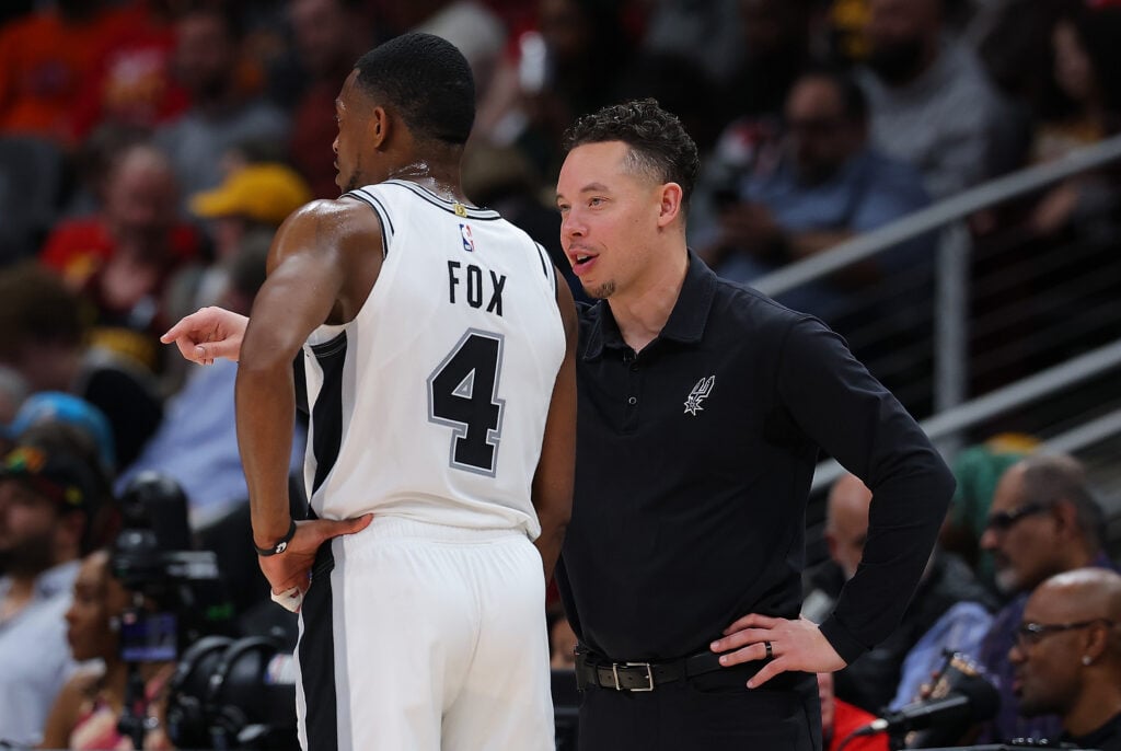 Head coach Mitch Johnson of the San Antonio Spurs converses with De'Aaron Fox #4 against the Atlanta Hawks during the second quarter at State Farm Arena.