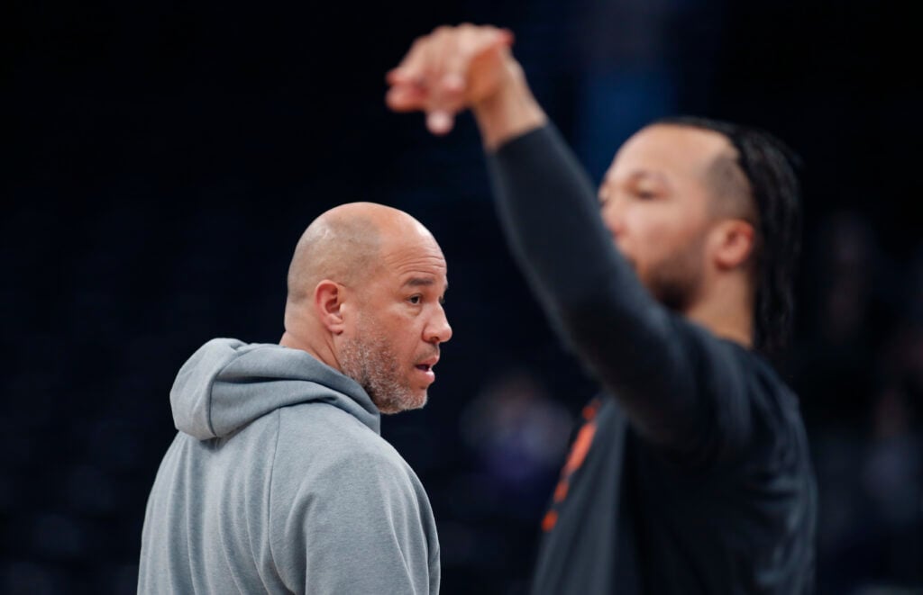 Assistant Coach Rick Brunson keeps an eye on Jalen Brunson #11 of the New York Knicks as he shoots during warmups before their game against the Utah Jazz at the Delta Center.