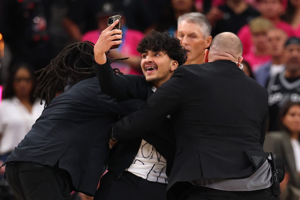 A fan is detained by security after running on the court during the fourth quarter of Game One of the 2026 NBA Finals between the San Antonio Spurs and the New York Knicks at Frost Bank Center on June 03, 2026 in San Antonio, Texas.